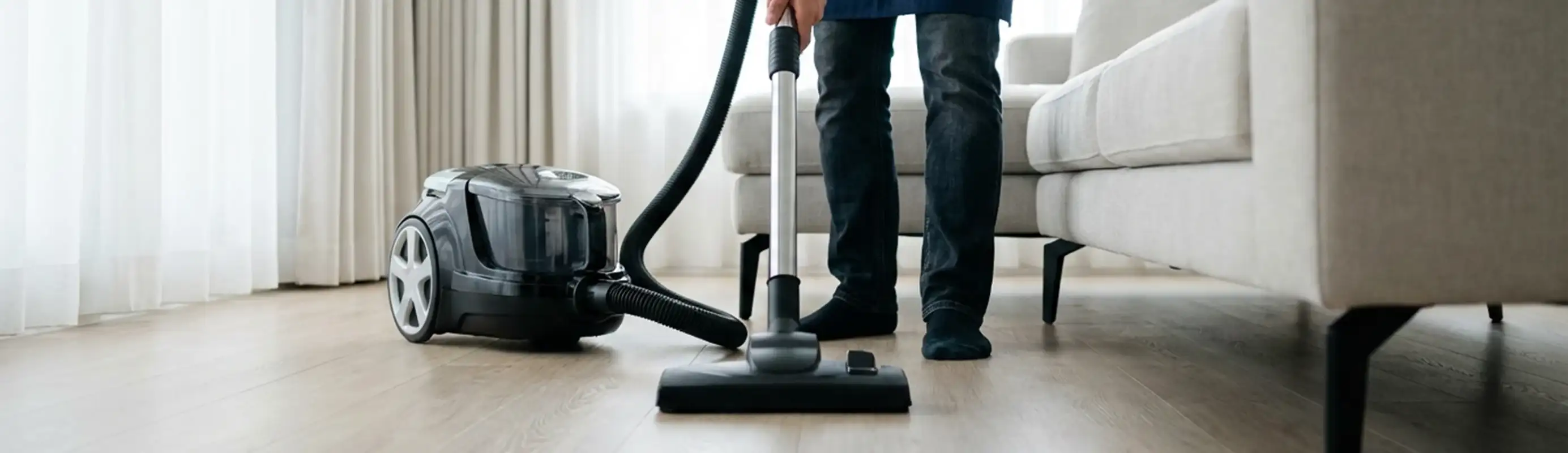 Professional house cleaner vacuuming a living room floor with a canister vacuum cleaner, Lakeland, FL.