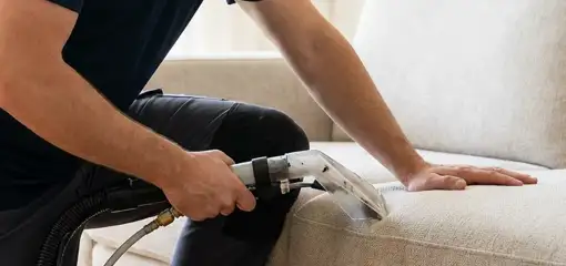 Professional upholstery cleaner deep-cleaning a fabric sofa with a handheld extraction tool, Lakeland, FL.